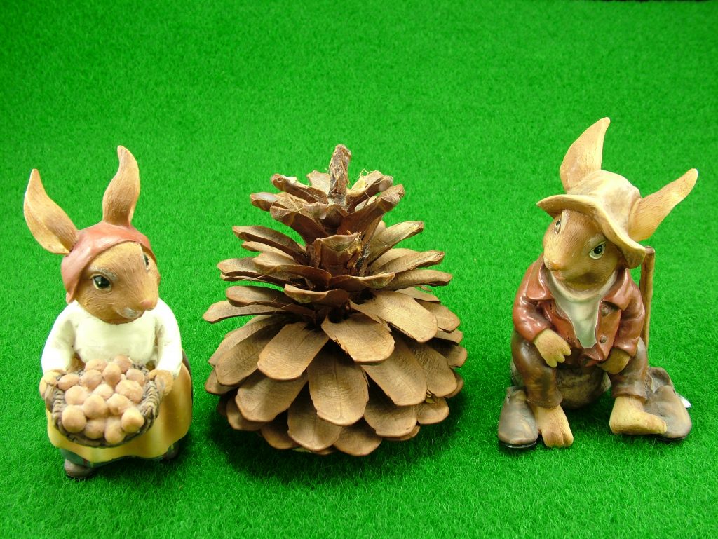 Påskeharer figurer i det grønne med nødder og grankogle. Påske fotokunst.